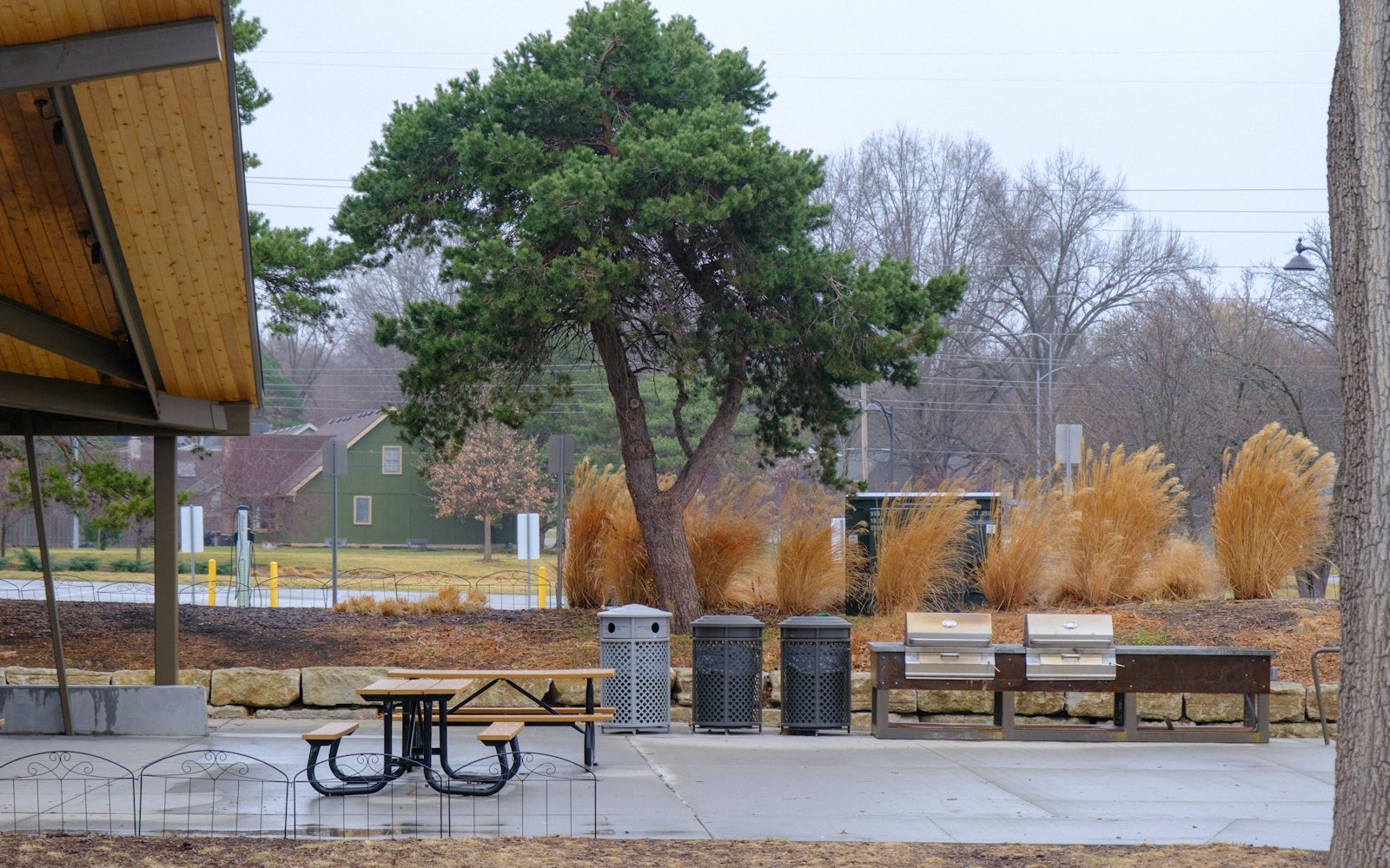 A covered picnic shelter with tables and a grill under large trees at Oakview Park.
